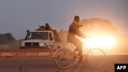 Un homme chevauche des gendarmes alors qu'ils gardent la route menant à la caserne militaire de la garde présidentielle d'élite (RSP), le 29 septembre 2015 à Ouagadougou.
