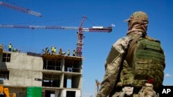 Seorang tentara Rusia menjaga lokasi gedung apartemen baru yang sedang dibangun dengan dukungan Kementerian Pertahanan Rusia, di Mariupol, di wilayah di bawah kendali Pemerintah Republik Rakyat Donetsk. (Foto: AP)