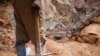 ARCHIVES - Un homme tenant une pioche regarde d'autres ouvriers travailler dans une mine de coltan près de la ville de Rubaya, dans l'est de la République démocratique du Congo, le 13 août 2019.