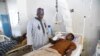 Le président du district de Kanam, Yusuf Dayyabu Garga (à gauche), s'occupe de Yahaya Musa, un survivant des attaques de bandits, dans l'État du Plateau, dans le centre-nord du Nigeria, le 23 avril 2022.
