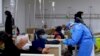In this photo released by Xinhua News Agency, a medical worker helps a patient at a community health care institution in Shanghai, China, Jan. 5, 2023. 