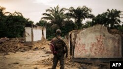 ARCHIVES - Un membre des forces armées congolaises se tient à côté d'un bâtiment incendié dans l'ouest de la République démocratique du Congo, le 1er février 2019.