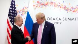 FILE - President Donald Trump and Russian President Vladimir Putin greet each other on the sidelines of the G-20 summit in Osaka, Japan, June 28, 2019.