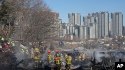Petugas pemadam kebakaran dan petugas penyelamat membersihkan lokasi kebakaran di desa Guryong di Seoul, Korea Selatan, Jumat, 20 Januari 2023. (AP/Ahn Young-joon)