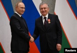 Presiden Rusia Vladimir Putin menganugerahkan Ordo Alexander Nevsky kepada Presiden Uzbekistan Shavkat Mirziyoyev dalam upacara di sela-sela KTT Organisasi Kerja Sama Shanghai (SCO) di Samarkand, Uzbekistan, 15 September 2022. (Foto: Sputnik/Dmitry Azarov via REUTERS)