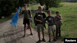 烏克蘭少年兒童在哈爾科夫地區的一處烏克蘭國土防衛軍訓練場地附近嬉戲。(2022年6月17日)