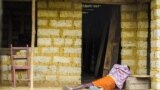 In this Tuesday, Oct. 21, 2014 file photo, a man suffering from the Ebola virus lies on the floor outside a house in Port Loko Community, on the outskirts of Freetown, in Sierra Leone. Ebola surveillance teams are going house-to-house in neighborhoods in 