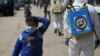 FILE - FILE - An internally displaced Syrian girl wears a face mask as members of the Syrian Civil defense sanitize the Bab Al-Nour internally displaced persons camp, to prevent the spread of coronavirus disease (COVID-19) in Azaz, Syria, March 26, 2020.