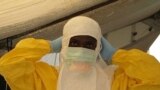 A health worker adjusts protective gear at a Doctors Without Borders' Ebola treatment unit in Conakry, Guinea. (VOA / Carol Guensburg) 