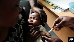 Une mère porte un enfant qui se fait administrer un nouveau vaccin contre le paludisme en essaie, au Centre du projet de recherche Reed (roseau) à Kombewa, Kenya, 24 juillet 2015. (AP Photo/Karel Prinsloo, Archives)
