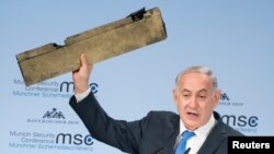 Le Premier ministre israélien Benjamin Netanyahu brandit une pièce d'un drone iranien qui aurait été abattu dans l'espace aérien israélien lors de son discours à la conférence de Munich sur la sécurité, en Allemagne, le 18 février 2018.
