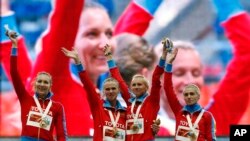 De gauche à droite, les athlètes russes Tatyana Firova, Yulia Gushchina, Kseniya Ryzhova, et Antonina Krivoshapka jubilent sur le podium avec leur médaille d'or au 4x400 mètres dames aux Championnats mondiaux d’athlétisme au stade de Luzhniki à Moscou, Russie, 17 août 2013.