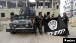 Des forces de sécurité irakienne tiennent un drapeau du groupe Etat islamique dans la province d'Anbar, 26 juillet 2015