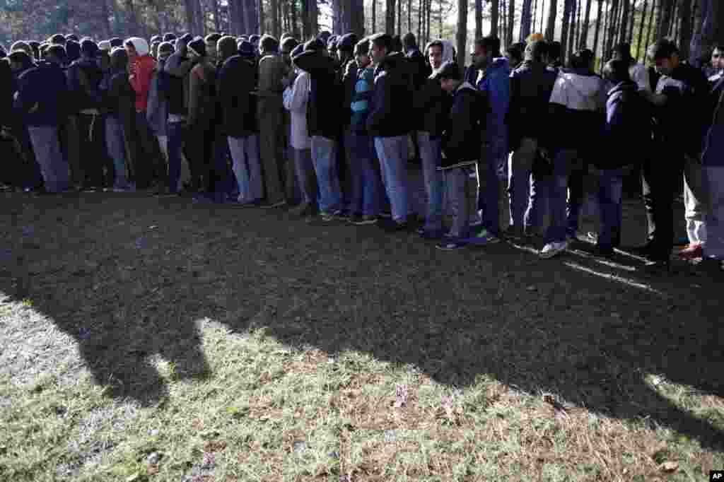 In this photo taken Tuesday, Nov. 19, 2013, migrants waiting for a meal in the center for asylum seekers in the village of Bogovadja, 50 Kilometers (30 Miles) south of Serbian capital, Belgrade form a line. 