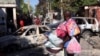 Un hombre que lleva sus pertenencias observa los restos de vehículos quemados durante el fin de semana por bandas armadas, mientras huye del suburbio de Poste Marchand, en Puerto Príncipe, Haití, el 9 de diciembre de 2024.