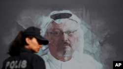 Une policière turque passe devant la photo du journaliste saoudien Jamal Khashoggi avant une cérémonie, près du consulat d'Arabie Saoudite à Istanbul, marquant le premier anniversaire de sa mort, le 2 octobre 2019.
