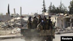 Des rebelles passent des bâtiments en ruine à al-Rai town, au nord d'Alep, Syrie, le 2 octobre 2016.