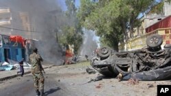Un soldat somalien se tient près de l'épave d'une voiture en feu, après une explosion, à Mogadiscio, Somalie, 1 octobre 2016.