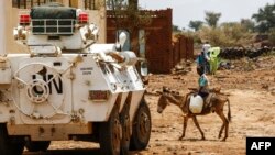 Un jeune soudanais traverse une route à dos d’âne devant une auto-blindée de la mission de l'Union des Nations Unies et de l'Union africaine à Darfour (Minuad), Soudan, 19 juin 2017.