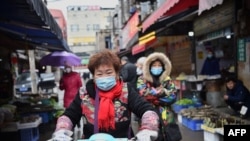一名戴著口罩的婦女騎著電動車穿過武漢市的一個市場。（2020年1月24日） 