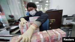 中國江蘇省南通市一家銀行的職員戴著口罩整理人民幣鈔票。（2020年1月30日）
