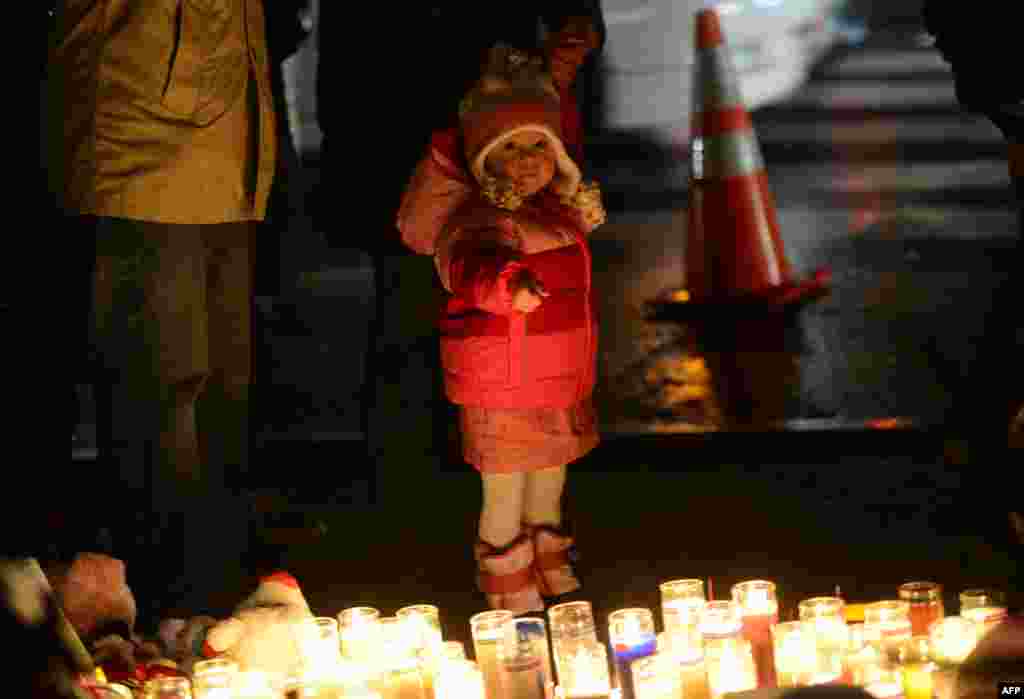 2012年12月16日，人們在一處臨時紀念龕憑吊小學槍擊案遇難者，一位男孩手指著蠟燭。