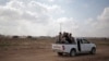 FILE - Palestinian Hamas gunmen ride on the back of a truck as they patrol the border with Israel near the southern Gaza Strip town of Khan Younis, as Israeli military bulldozers are seen in the background, June 10, 2015.