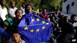 Un migrant portant un drapeau de l'Union européenne assis par terre avec d'autres après avoir pris d'assaut une clôture pour entrer dans l'enclave espagnole de Ceuta, Espagne, 17 février 2017.