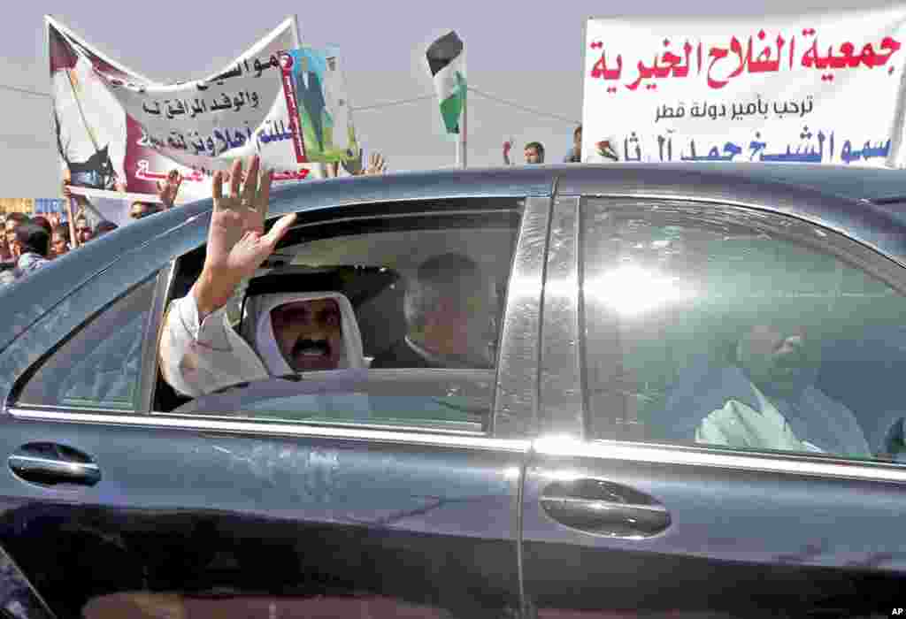 The Emir of Qatar Sheikh Hamad bin Khalifa al-Thani waves to crowds as he sits next to Gaza&#39;s Hamas prime minister Ismail Haniyeh following a welcome ceremony in Rafah, southern Gaza Strip, Tuesday, October 23, 2012. 