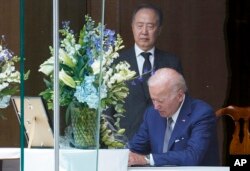 President Joe Biden signs a condolence book at the Japanese ambassador's residence in Washington, Friday, July 8, 2022, for former Japanese Prime Minister Shinzo Abe who was assassinated on Friday while campaigning. Japanese Ambassador to the United States Koji Tomita looks on.
