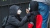 FILE - A woman adjusts her child's protective mask as they wait in line to be screened for COVID-19 at Gotham Health East New York, April 23, 2020, in the Brooklyn borough of New York City. 