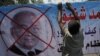 An Egyptian youth hangs a banner with a defaced picture of presidential candidate, Ahmed Shafiq and Arabic that reads "Shafiq, the former regime," during a protest in front the Supreme Constitutional Court in Cairo, Egypt, Thursday, June 14, 2012.