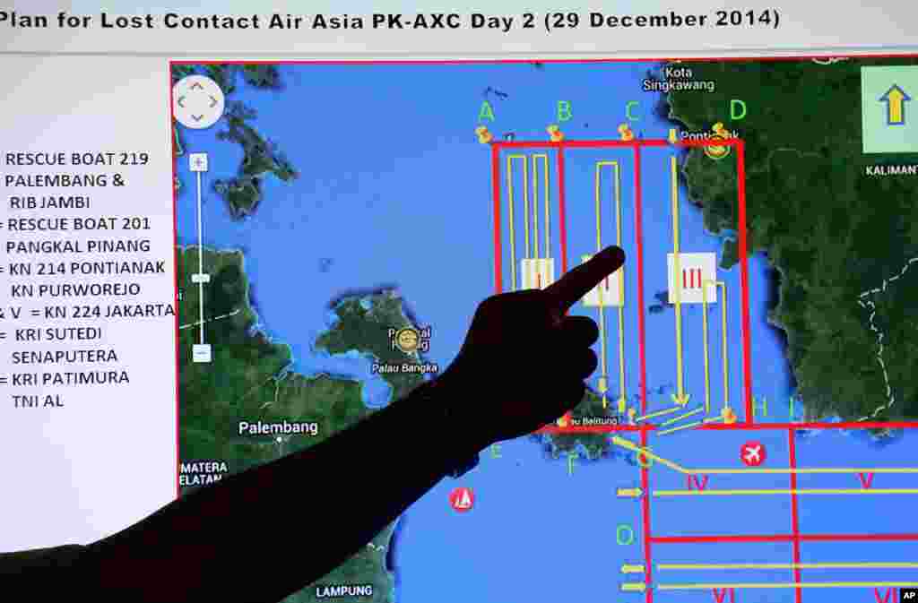 Un membre de l&#39;Agence nationale indonésienne de recherche et de sauvetage (Basarnas) pointe un doigt à une carte d&#39;une zone de recherche lors d&#39;un briefing avant une opération de recherche et sauvetage d el&#39;avion d&#39;AirAsia disparu, décembre . 29, 2014.
