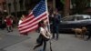 A girl parades up and down her block with a U.S. flag on her scooter, in the Greenwich Village neighborhood, during a partial easing of coronavirus restrictions in New York, May 14, 2020.