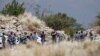 La police fouille des personnes avant qu’elles ne rentrent dans le puit pour négocier avec les mineurs clandestins pour leur retour à la surface à Stilfontein, le 13 novembre 2024.