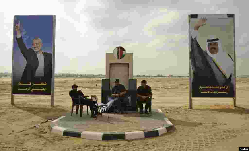 Members of Hamas security forces sit between posters depicting senior Hamas leader Ismail Haniyeh (L) and Qatar&#39;s Emir Sheik Hamad bin Khalifa al-Thani (R) in Khan Younis in the southern Gaza Strip October 22, 2012. 
