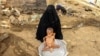 FILE - Moaz Ali Mohammed, a two-year-old Yemeni boy from an impoverished family in the Bani Amer region, who suffers from acute malnutrition, is bathed by his mother outside their house in the Aslam district in the northern Hajjah province, July 28, 2019.