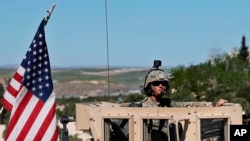 Un soldat américain assis sur son véhicule blindé sur une route menant à la ligne de front tendue à Manbij, Syrie, 4 avril 2018.