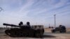 Sebuah mobil bergerak melewati tank yang terabaikan di Aleppo, Suriah, pada 11 Desember 2024. (Foto: Reuters/Karam al-Masri)