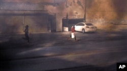 Masked Bahraini anti-government protesters run through smoke after setting tires alight on a road in the village of Dumistan, January 7, 2013.