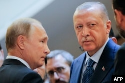 Russian President Vladimir Putin, left, and Turkish President Recep Tayyip Erdogan wait to enter a hall during their meeting at the Bocharov Ruchei residence in the Black Sea resort of Sochi, in Sochi, Sept. 17, 2018.