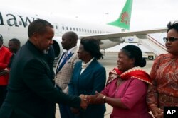 Wakil Presiden Malawi Saulos Chilima, kiri, menyapa pejabat pemerintah sekembalinya dari Korea Selatan di Lillongwe, Minggu, 9 Juni 2024. (Foto: AP)