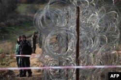 Border police stand guard next to a border fences which are planned to be built on the Bulgarian border with Turkey, near the village of Golyam Dervent on November 28, 2013. AFP PHOTO / NIKOLAY DOYCHINOV