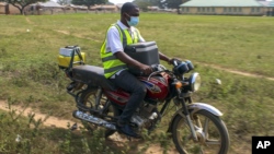 Yunusa Bawa, un agent de santé communautaire, circule sur une moto avec une boîte de vaccins contre le coronavirus d'AstraZeneca, à Sabon Kuje, dans la banlieue d'Abuja, au Nigeria, le 6 décembre 2021.
