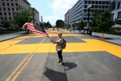 Beth Shafa waves an American flag near the White House, June 5, 2020. City workers and activists painted the words Black Lives Matter in enormous bright yellow letters on the street leading to the White House.