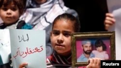 A Palestinian girl holds a photograph of her father, who is being held in a Palestinian prison, during a protest in the West Bank city of Ramallah, in support of prisoners who were allegedly arrested because of their affiliation with Hamas, May 14, 2013.
