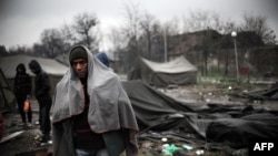 A man stands by tents as snow falls in a refugee camp set in the Bulgarian town of Harmanli, south-east of Sofia, on November 27, 2013. AFP