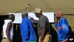 Watu wakiangalia baadhi ya matokeo ya uchaguzi nje ya ofisi za kupiga kura mjini Harare, Zimbabwe, Julai 31, 2018.
