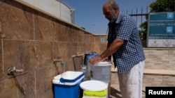 FILE - A man fills jerrycans with water in Derna, Libya, June 13, 2018. Sunday, an armed group stormed Tripoli's main water distribution station, imperiling water supplies for up to two million people.