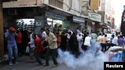 Protesters and shoppers run for cover from a sound grenade thrown by riot police to disperse protesters, during an anti-government protest in the capital Manama, October 26, 2012. 